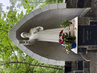Stone statue of Saint Charbel with flowers at the National Shrine Grotto of Our Lady of Lourdes in Maryland